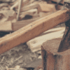 An axe stuck in a log with chopped wood behind it